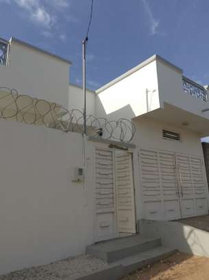 Maison moderne blanche avec portail sécurisé et barbelés image 1
