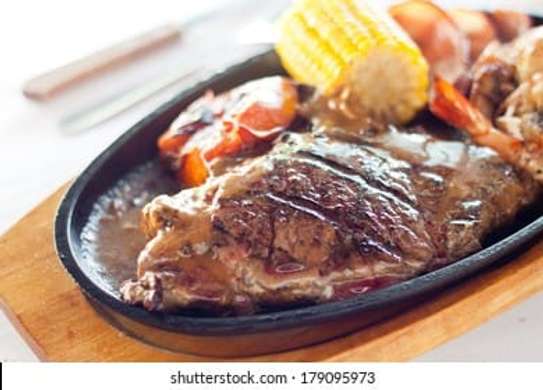 Cast iron hot sizzling plate on wooden tray image 1